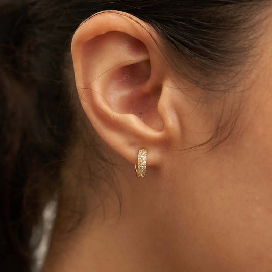 Model wearing Crystal Huggies White earrings close-up on ear, showcasing their sparkling design.